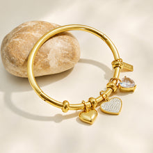 Gold heart bangle bracelet showing smooth and zircon-set heart charm details