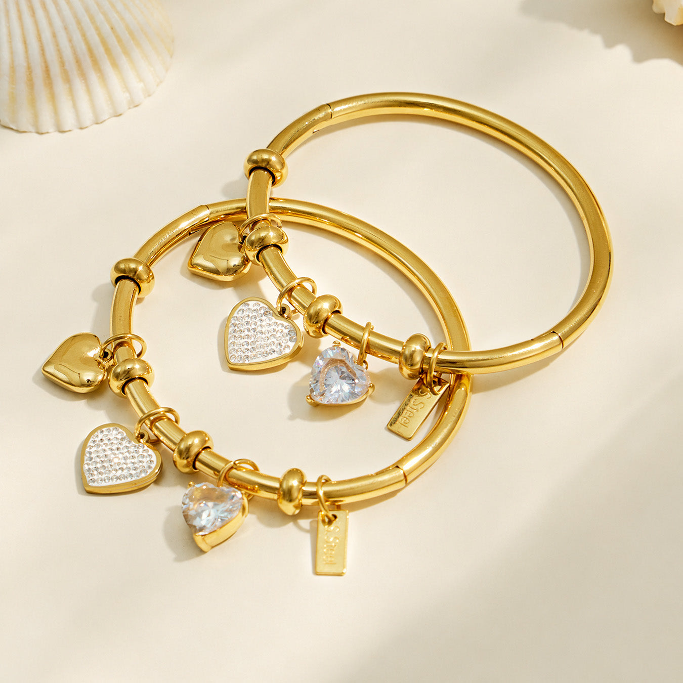 Gold heart charm bangle bracelet displayed in a neutral flat lay