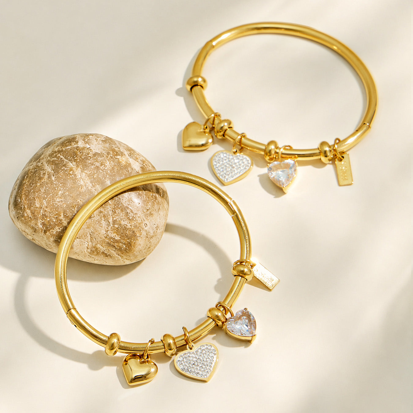 Gold heart charm bangle bracelets arranged together on a neutral background