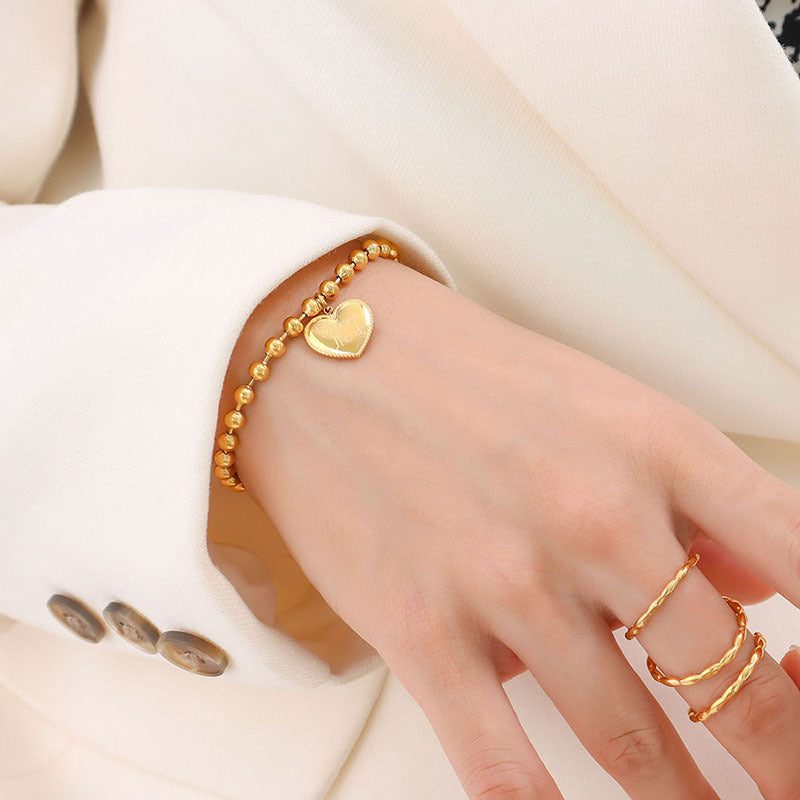 Gold heart charm beaded bracelet worn on the wrist