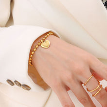 Gold heart charm beaded bracelet worn on the wrist