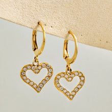 Gold heart cubic zirconia drop earrings displayed on a neutral background