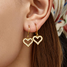 Gold double heart drop earrings styled on the ear