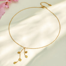 Gold heart drop Y necklace arranged in a circular flat lay with dangling charms