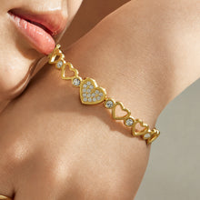 Close-up of a gold tone 316L stainless steel heart link bracelet held in hand