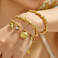 Close-up of a model wearing gold heart-link and ocean charm bracelets together