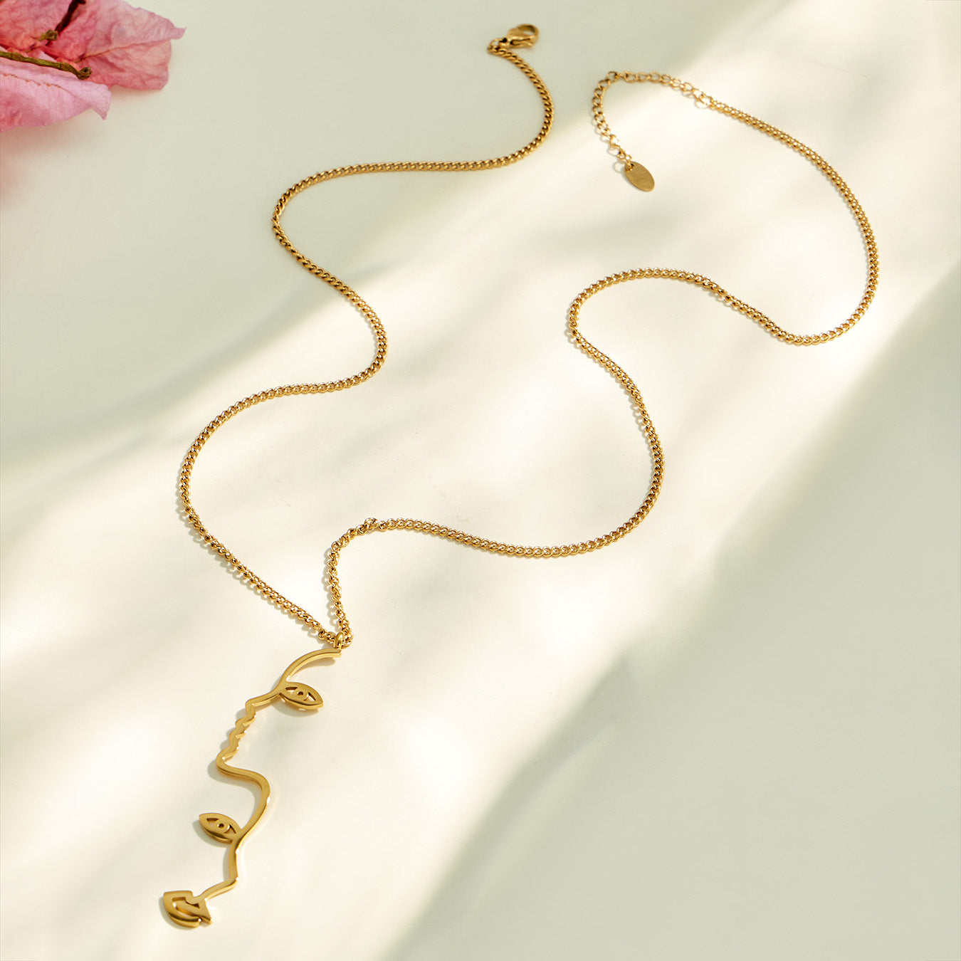 Gold heart tassel Y necklace arranged in a flowing flat lay on neutral fabric