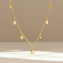 Gold heart charm necklace with spaced teardrop zircon accents on display