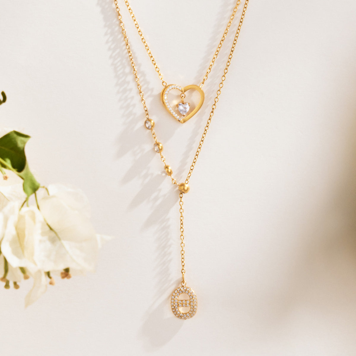Gold-tone heart pendant and Y necklaces displayed with floral styling