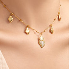 Close-up of gold-tone heart zircon charm necklace with multiple dangling heart details