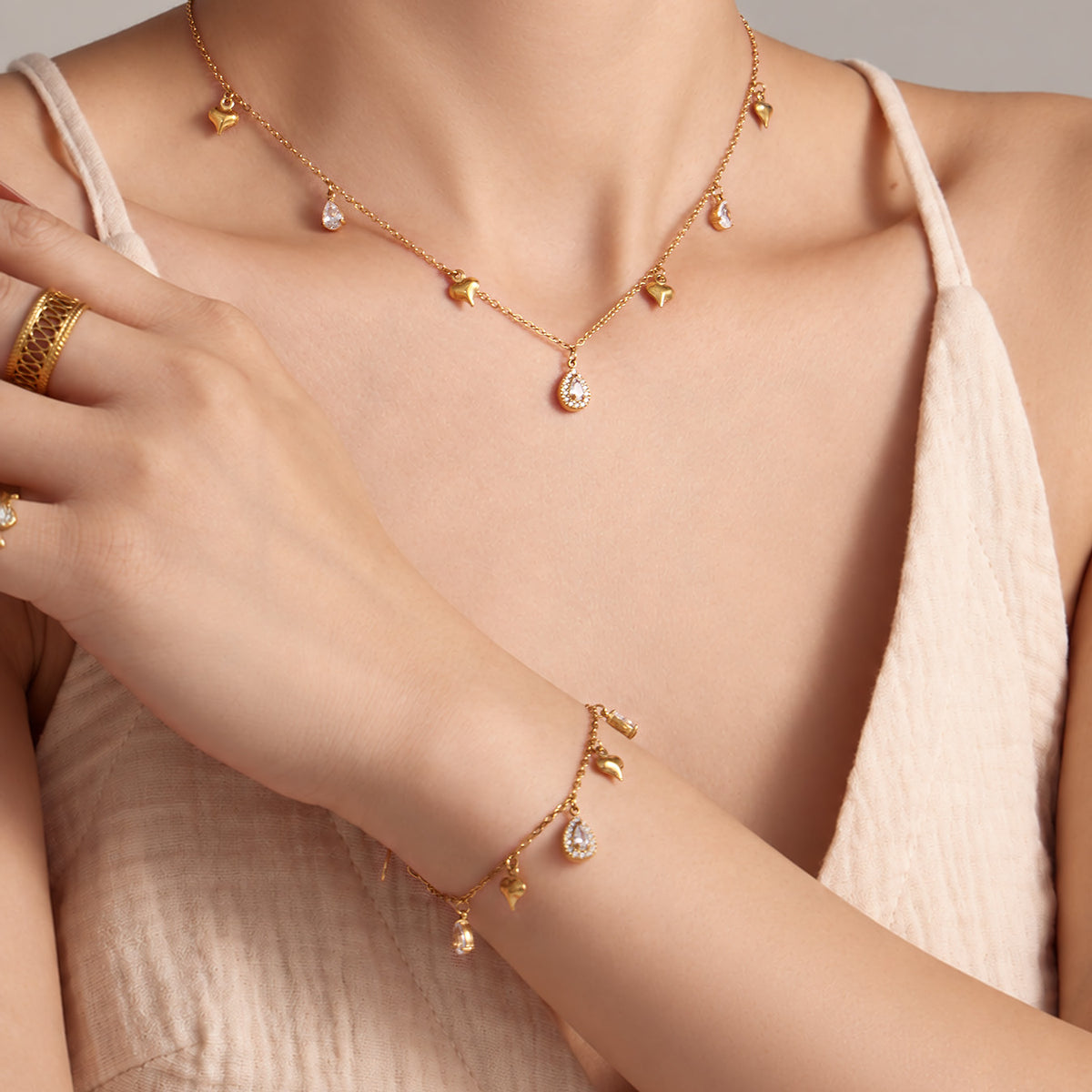 Gold heart zircon charm necklace and matching bracelet styled on model