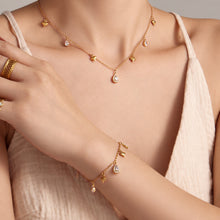 Gold heart zircon charm necklace and matching bracelet styled on model