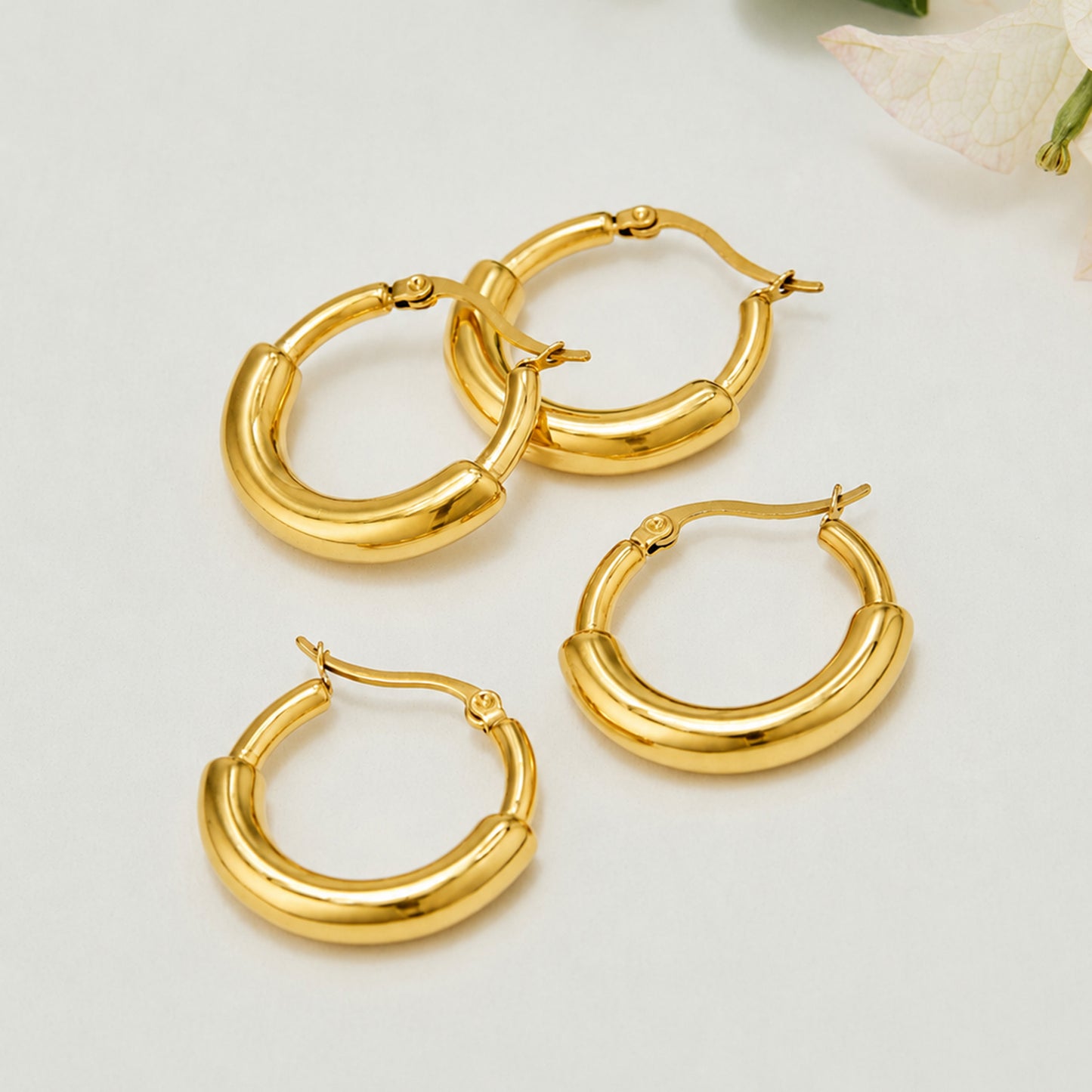 Multiple gold C-shaped hoop earrings arranged in a polished product display