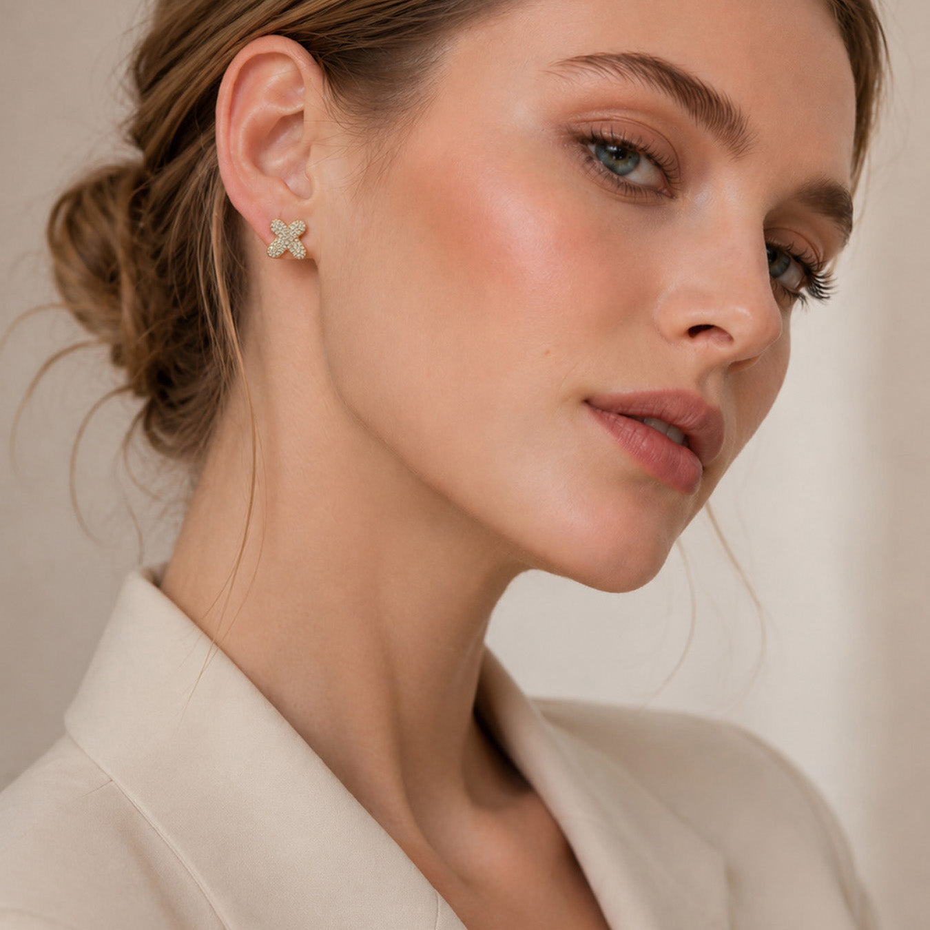 Model wearing small gold initial letter stud earrings