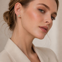Model wearing small gold initial letter stud earrings