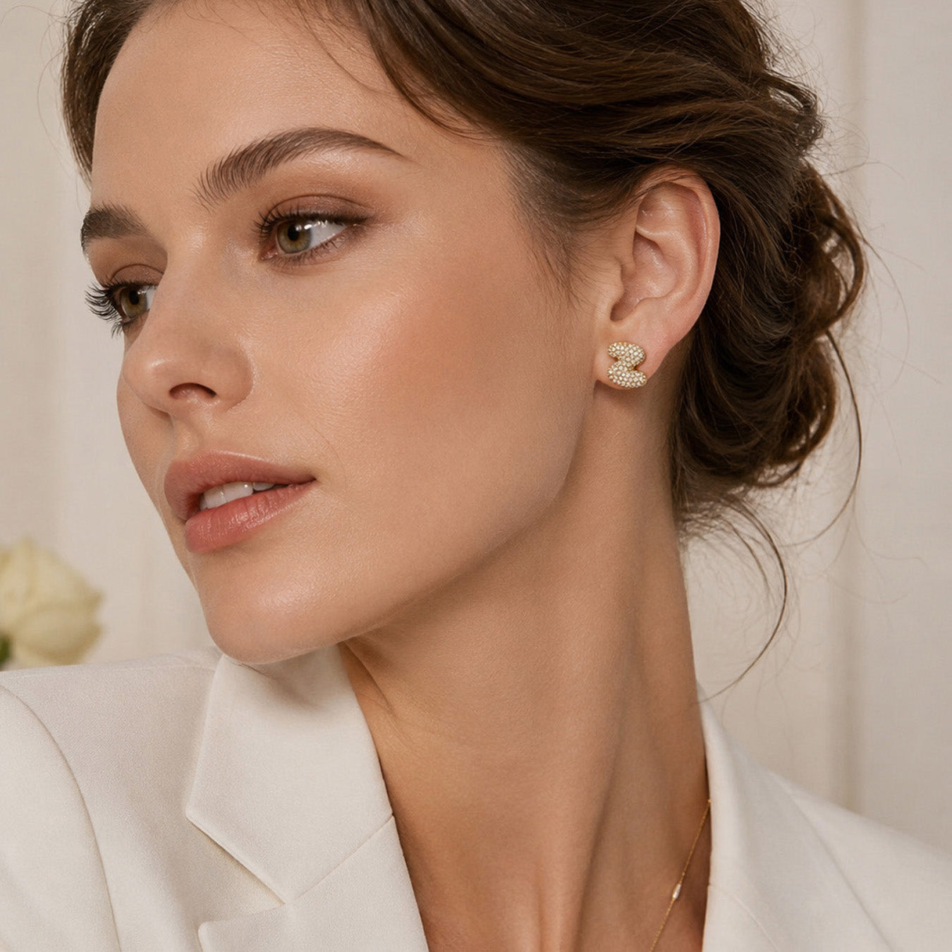 Side view of model wearing gold initial stud earrings