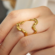 Close-up of a gold 316L stainless steel irregular open ring worn on a model finger