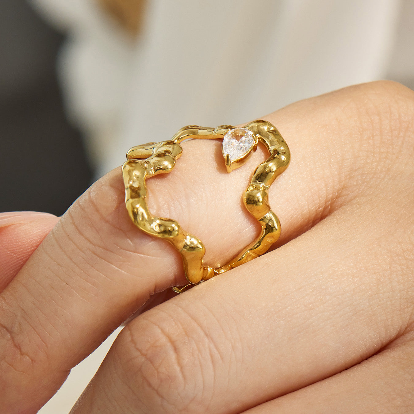Close-up detail of a gold irregular 316L stainless steel ring with polished organic silhouette