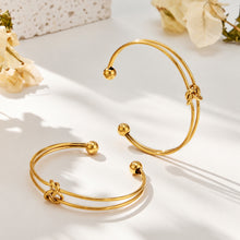 Two gold-tone knot cuff bracelets shown at different angles with open cuff structures