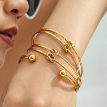 Gold-tone knot cuff bracelet styled on wrist for minimalist everyday wear