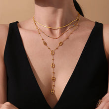 Model wearing a gold tone layered stainless steel tassel necklace with a black dress