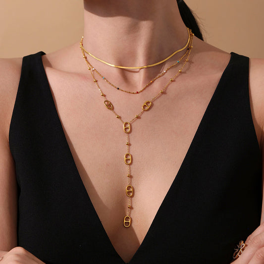 Model wearing a gold tone layered stainless steel tassel necklace with a black dress