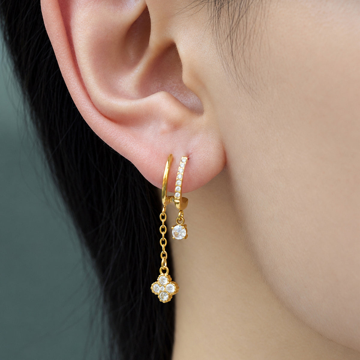 Gold-tone stainless steel long CZ charm earrings shown close up on ear