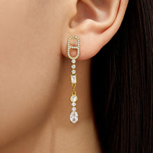Model wearing long gold cubic zirconia drop earrings with clear stone accents