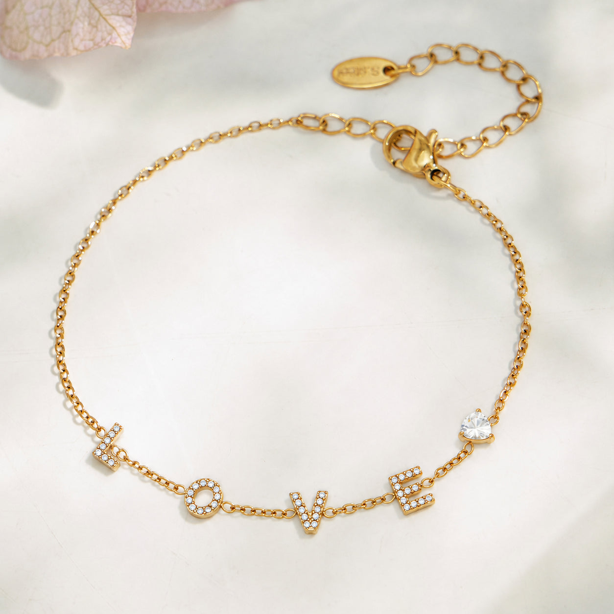 Gold LOVE letter zircon bracelet with adjustable extender chain in a flat lay