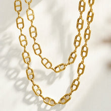 Layered gold mariner chain link necklaces displayed on a light textured surface