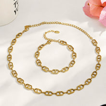 Gold mariner chain link necklace and bracelet arranged together in a circular flat lay