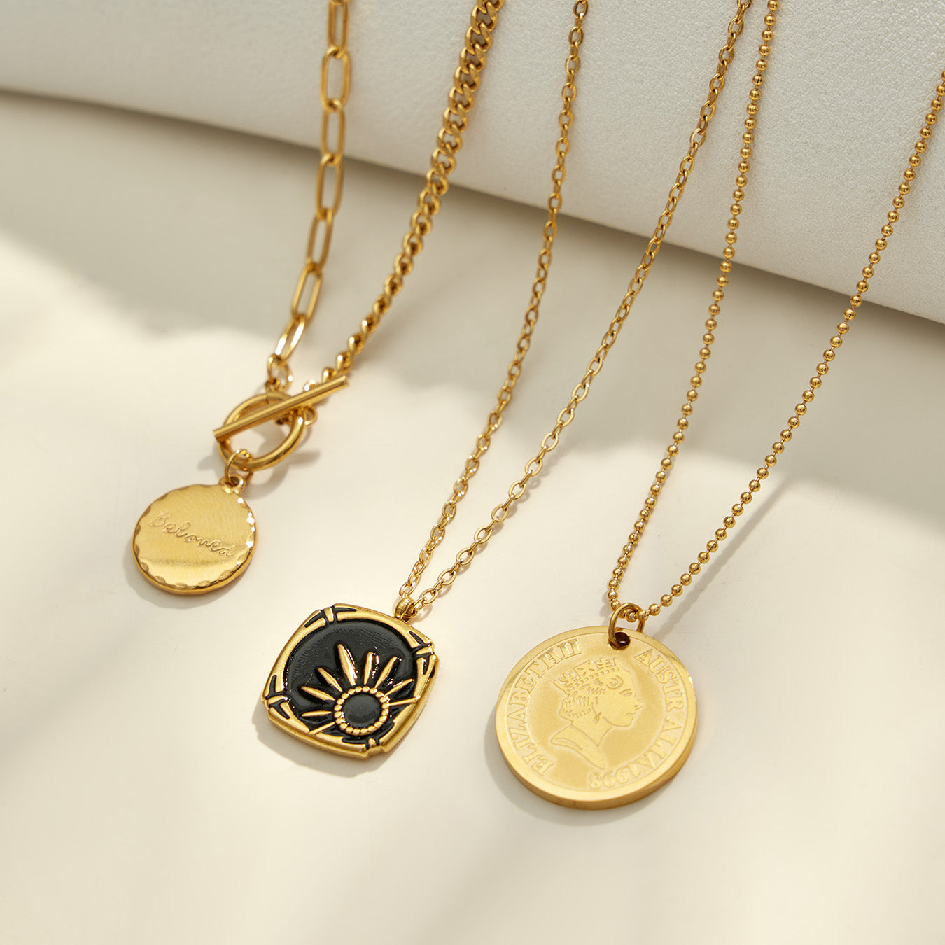 Gold round medallion, celestial and black enamel pendant necklaces displayed together