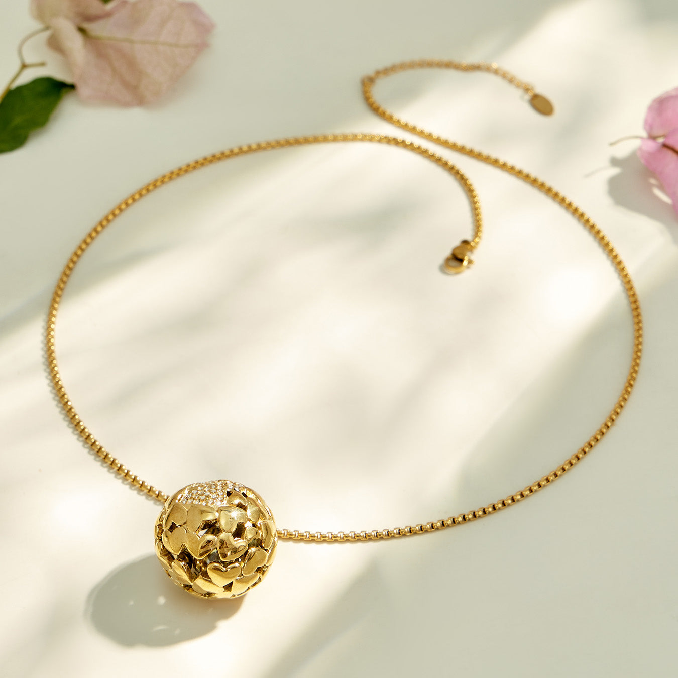 Gold medallion pendant necklace arranged in a circular flat lay on cream fabric