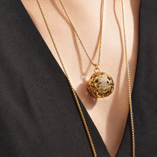 Gold medallion pendant necklace styled over a black V-neck outfit
