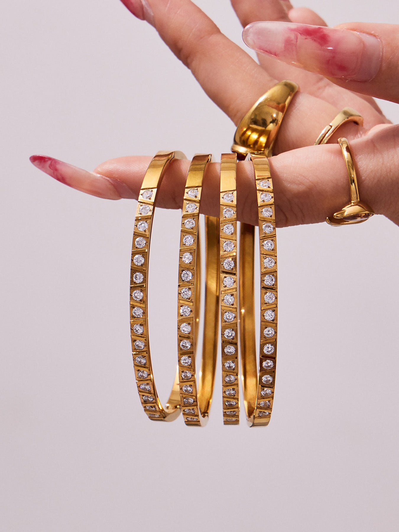 Gold minimalist bangle collection with varied surface details held in hand