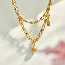 Layered gold pendant, chain link and lariat necklaces shown in a close-up display