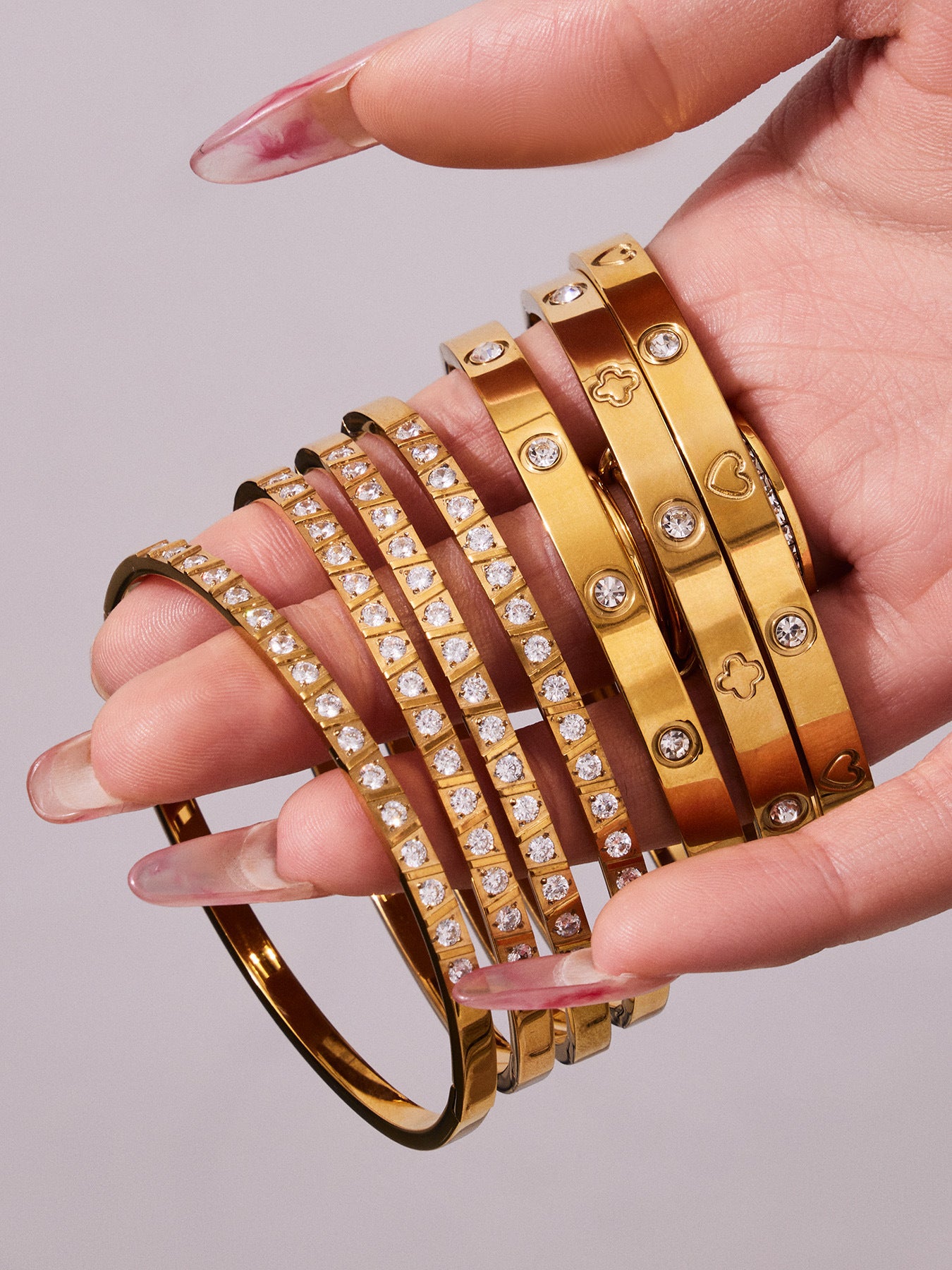 Hand holding multiple gold minimalist stackable bangles for layered styling
