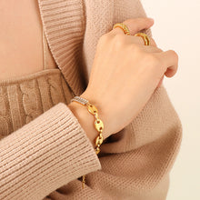 Model wearing a gold-tone mixed-link bracelet with clear rectangular zircon on the wrist