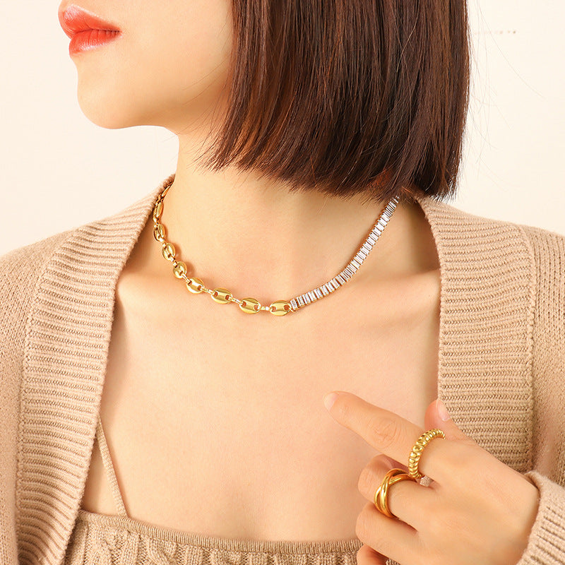 Model wearing a gold-tone mixed-link necklace with elongated links and clear rectangular zircon