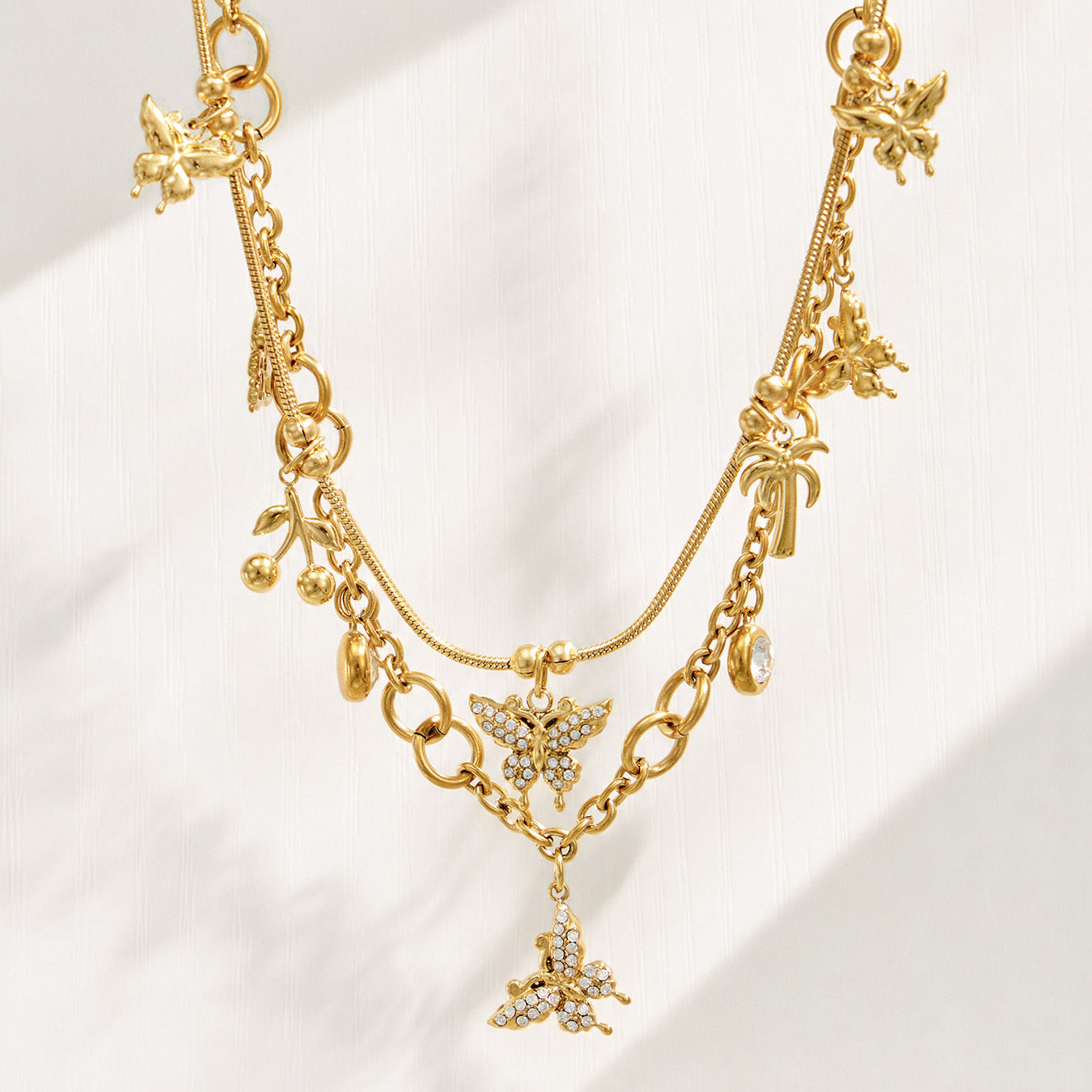 Gold multi-charm butterfly necklace displayed vertically to show the charm arrangement