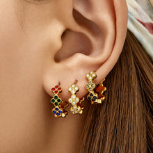 Gold multicolor cubic zirconia clover huggie earrings worn on the ear