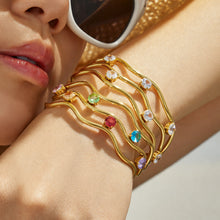 Close-up of a gold open bangle with multicolor cubic zirconia accents