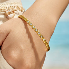 Close-up of a gold bangle with multicolor zircon details on a model wrist