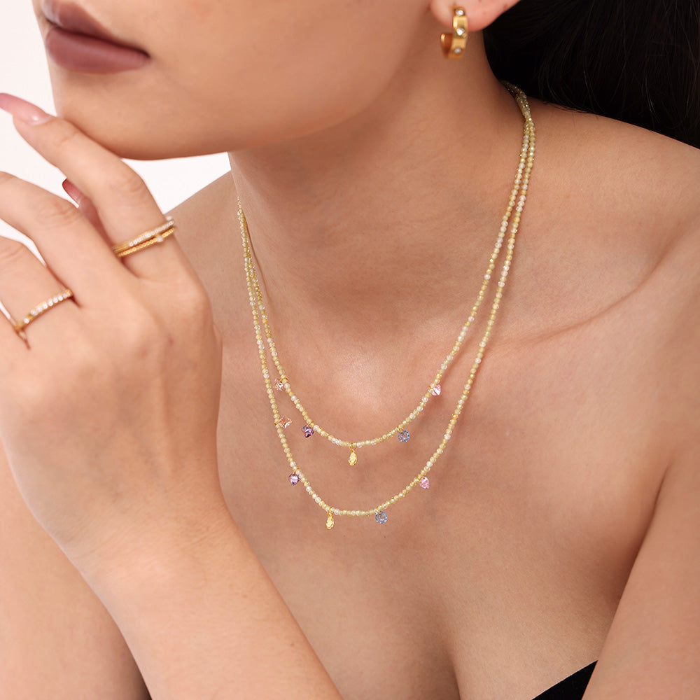 Model wearing a gold stainless steel necklace with colorful natural stone bead accents