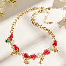 Gold-tone ocean animal charm necklace with red bead, shell and sea life details