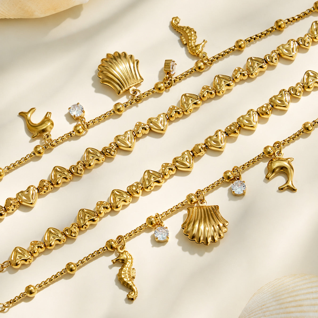 Close-up of a gold ocean charm bracelet with sea-life charms and beaded chain details