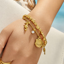 Model wearing a gold ocean charm bracelet with shell and clear cubic zirconia accents