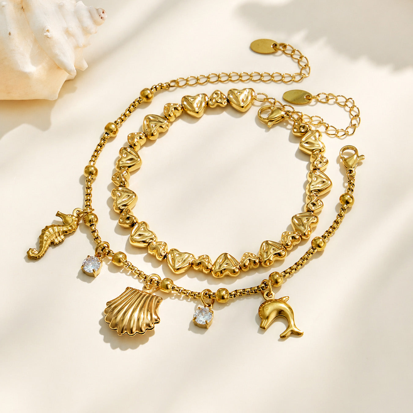 Gold ocean charm bracelet displayed with shell, seahorse and clear cubic zirconia details