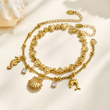 Gold ocean charm bracelet displayed with shell, seahorse and clear cubic zirconia details