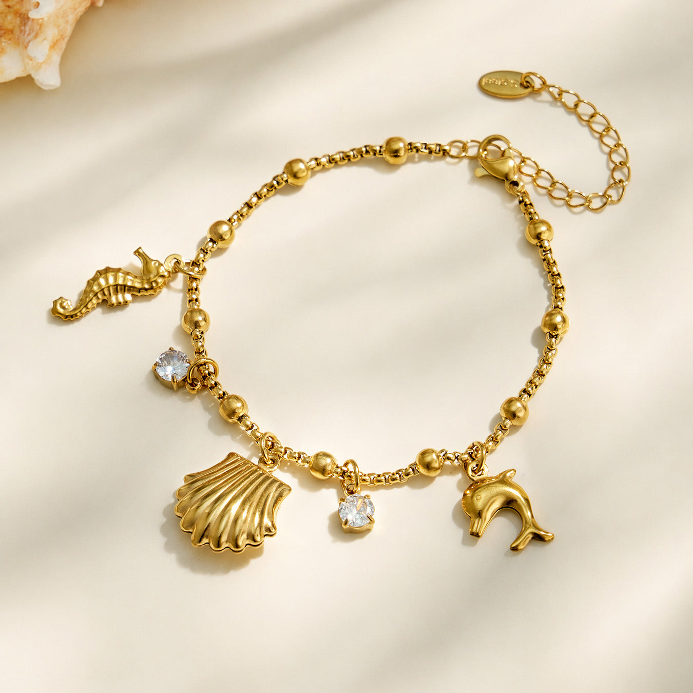 Gold ocean charm bracelet with shell, seahorse and clear cubic zirconia accents